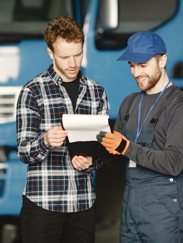 Vehicle fleet engineers and commercial technicians collaborating in a service facility with diagnostic tablets and heavy-duty vehicles.