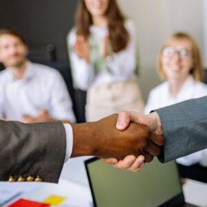 Close-up of a handshake between colleagues in a professional office setting, emphasizing teamwork and agreement.